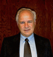 Photo of Professor Bridges in suit and tie against a red background.